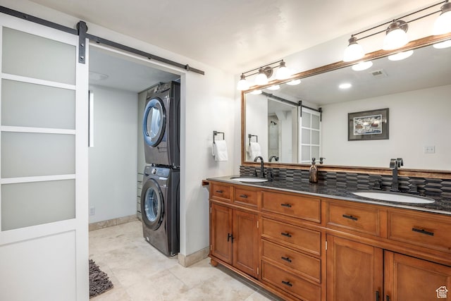 full bathroom with stacked washing maching and dryer, visible vents, baseboards, and a sink