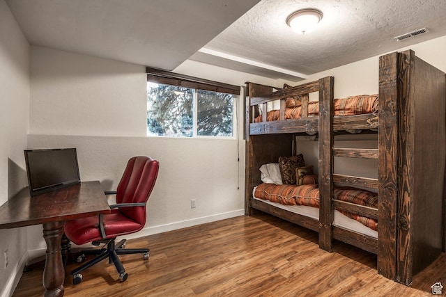 bedroom with visible vents, baseboards, a textured ceiling, and wood finished floors