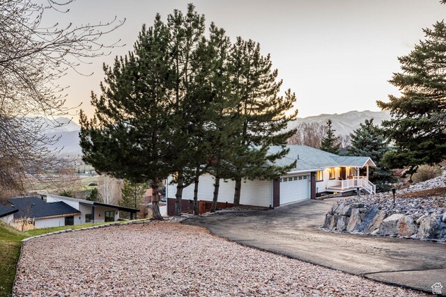 view of front of home featuring a mountain view, a porch, a garage, and aphalt driveway