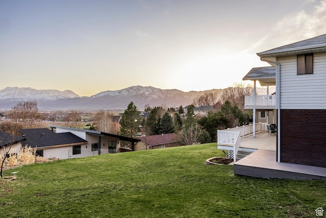 yard at dusk featuring a deck with mountain view and a balcony