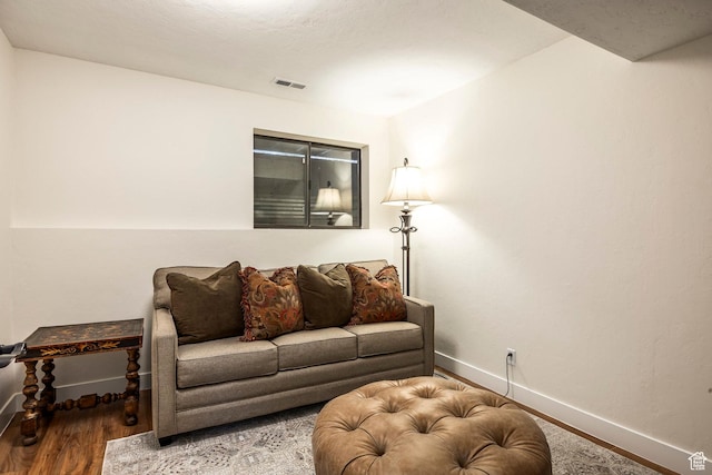 living room with visible vents, baseboards, and wood finished floors