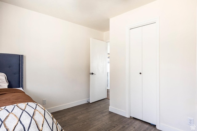 bedroom with a closet, baseboards, and dark wood finished floors