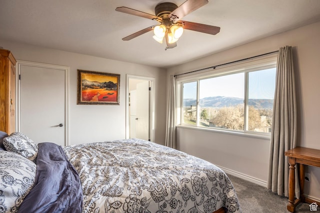 bedroom featuring a mountain view, dark carpet, baseboards, and a ceiling fan