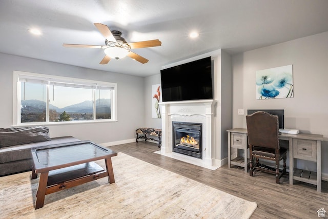 living area featuring ceiling fan, a fireplace, recessed lighting, wood finished floors, and baseboards
