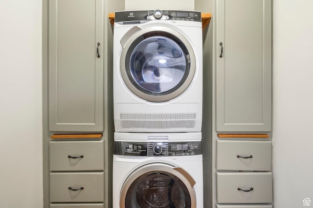 clothes washing area featuring stacked washer / dryer and cabinet space