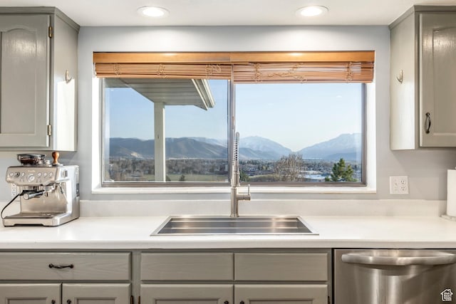 kitchen with a mountain view, a sink, a wealth of natural light, gray cabinets, and stainless steel dishwasher