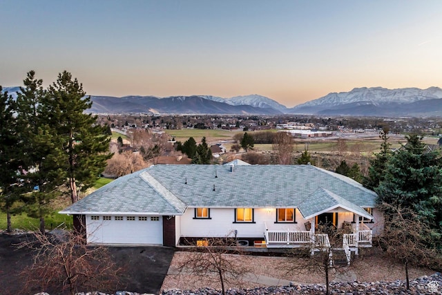 view of front of house featuring a garage, aphalt driveway, a mountain view, and covered porch