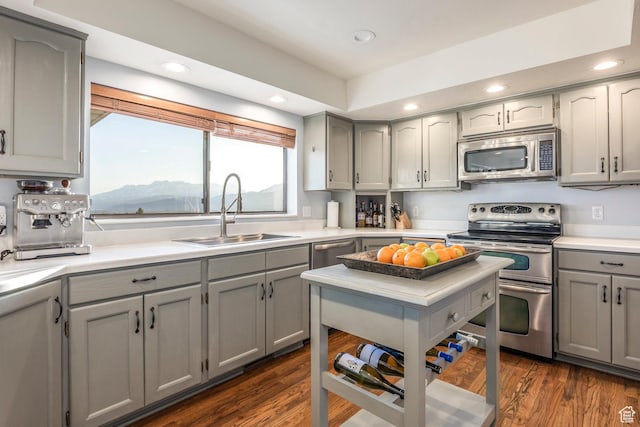 kitchen with recessed lighting, gray cabinets, a sink, light countertops, and stainless steel appliances