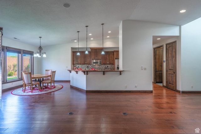 1844 N Wellington St, Washington, UT 84780 - kitchen featuring stainless steel appliances, tasteful backsplash, a breakfast bar, dark wood finished floors, and a notable chandelier