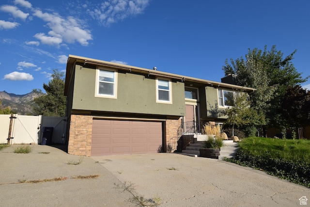 9111 S Parakeet Dr, Sandy, UT 84093 - bi-level home with concrete driveway, fence, stone siding, a garage, and a gate