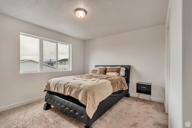 bedroom with carpet, baseboards, and a textured ceiling