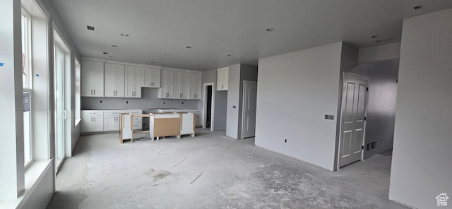 kitchen with white cabinetry, visible vents, and concrete flooring