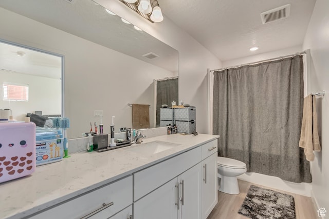 full bathroom featuring visible vents, toilet, vanity, and wood finished floors