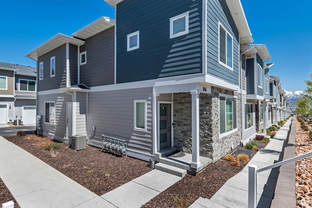 view of side of property with central air condition unit and stone siding