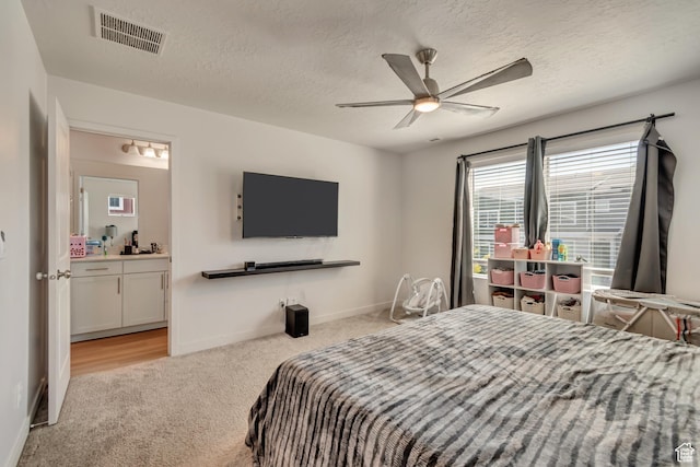 bedroom with carpet, visible vents, baseboards, and a textured ceiling