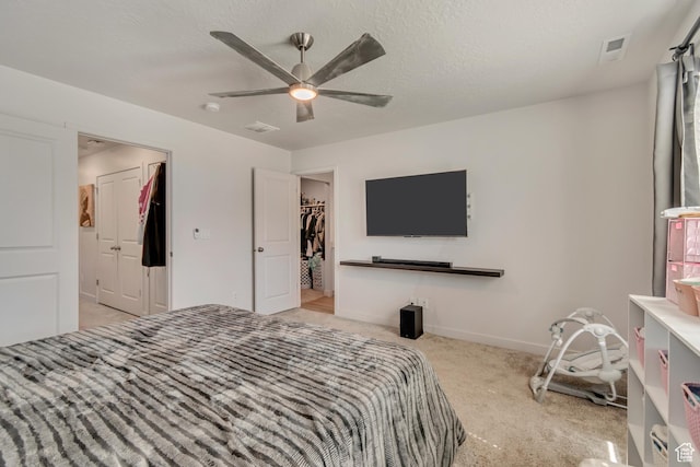 bedroom featuring visible vents, baseboards, ceiling fan, carpet floors, and a walk in closet