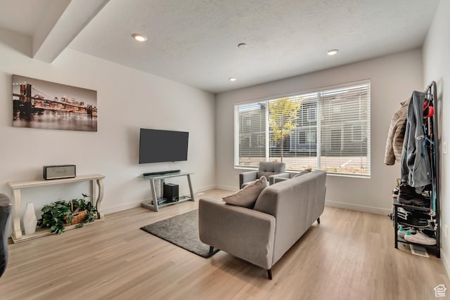 living area featuring baseboards, recessed lighting, light wood-style floors, and a textured ceiling