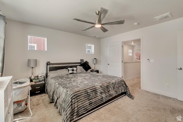 bedroom with light colored carpet, ceiling fan, multiple windows, and visible vents