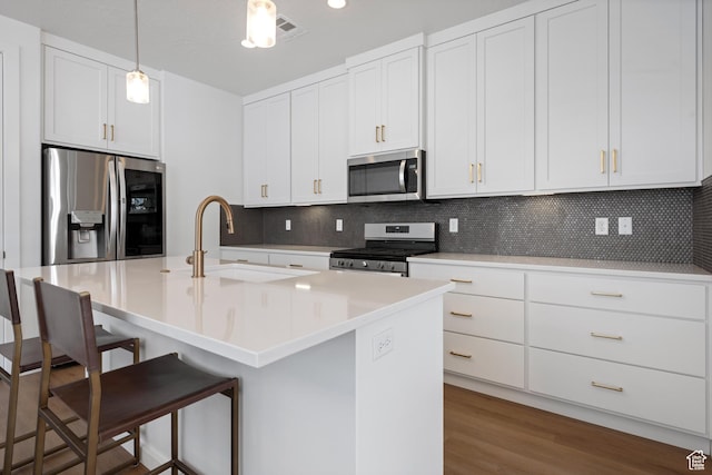 kitchen featuring tasteful backsplash, decorative light fixtures, a sink, a kitchen breakfast bar, and stainless steel appliances