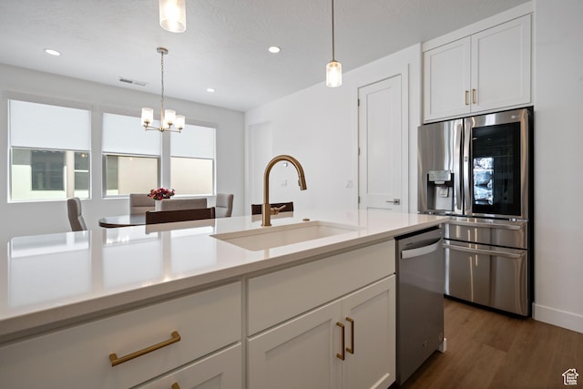 kitchen featuring light countertops, white cabinets, decorative light fixtures, stainless steel appliances, and a sink