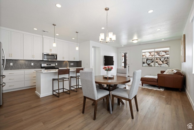 dining room featuring recessed lighting, visible vents, an inviting chandelier, and wood finished floors