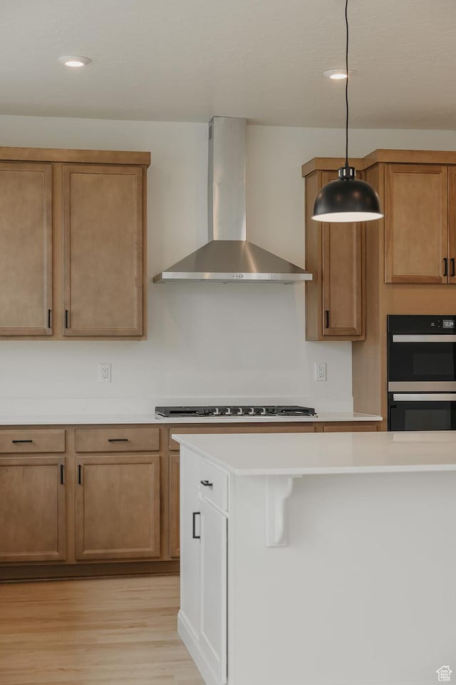 kitchen with wall chimney exhaust hood, light wood-type flooring, stainless steel gas stovetop, light countertops, and recessed lighting