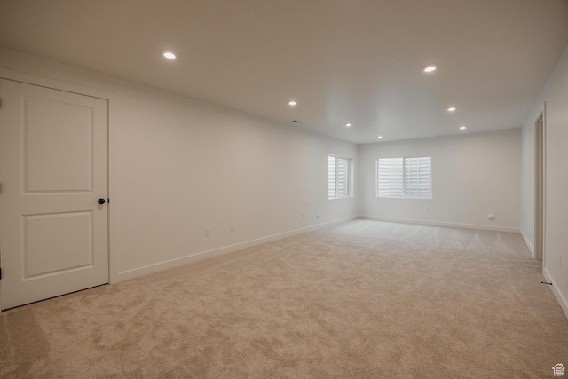 empty room with light colored carpet, recessed lighting, and baseboards