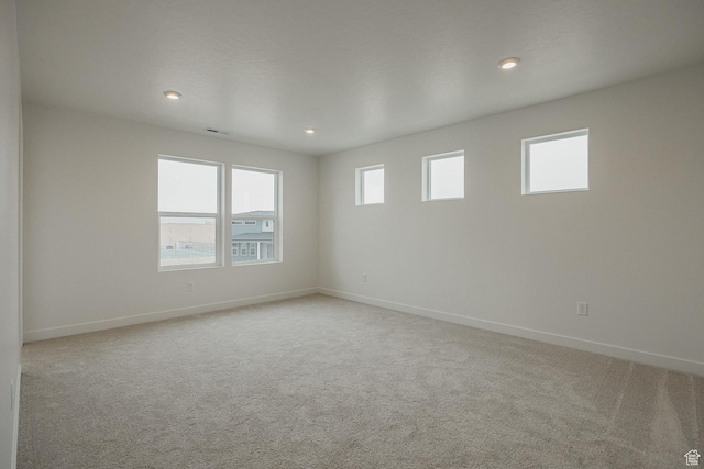 spare room featuring light carpet, baseboards, and recessed lighting