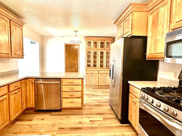 kitchen featuring stainless steel appliances, light wood finished floors, a peninsula, a textured ceiling, and hanging light fixtures