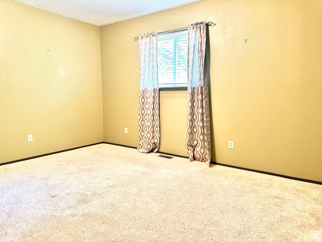 carpeted spare room featuring a textured ceiling and baseboards