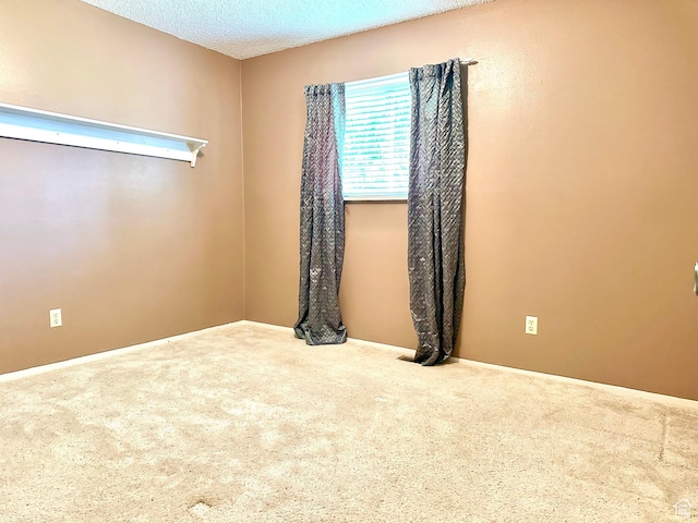 empty room featuring carpet floors, baseboards, and a textured ceiling