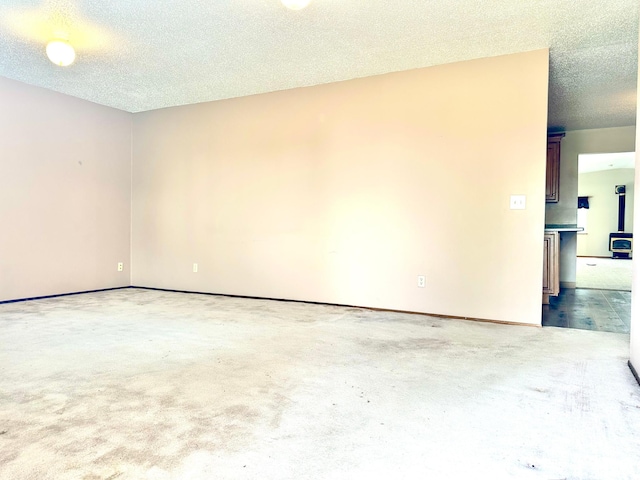 unfurnished room with carpet floors, a textured ceiling, and baseboards