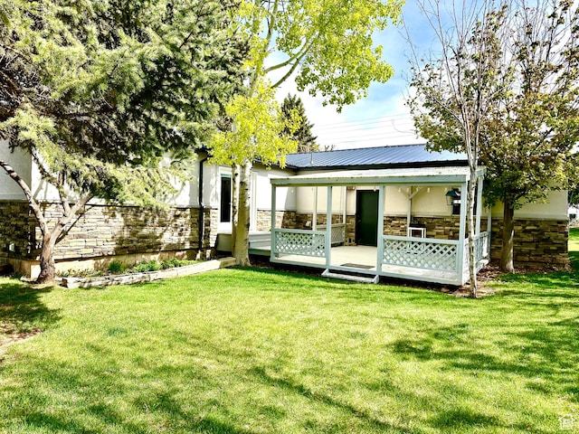 back of house with stone siding and a lawn