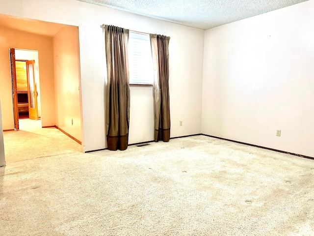 unfurnished room featuring carpet, baseboards, and a textured ceiling