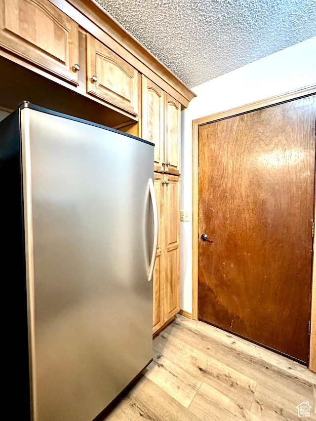 kitchen with freestanding refrigerator, light wood-style flooring, and a textured ceiling