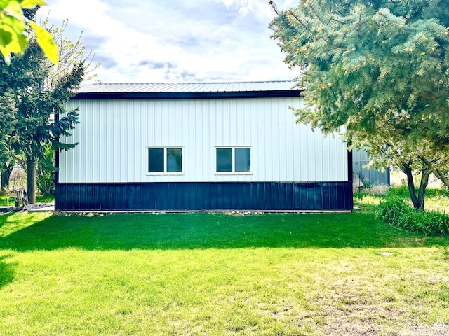 view of side of property featuring a lawn and metal roof