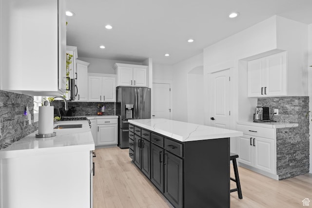 4634 W Baldy Dr, West Jordan, UT 84088 - kitchen featuring decorative backsplash, a kitchen island, white cabinets, stainless steel fridge with ice dispenser, and dark cabinetry