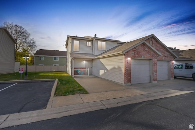 traditional-style house with a garage, a yard, fence, brick siding, and driveway