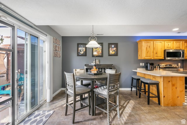 dining space with light tile patterned floors, visible vents, baseboards, and a textured ceiling
