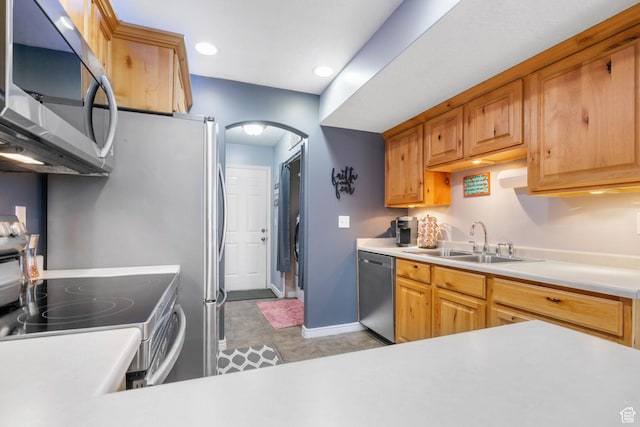 kitchen with baseboards, light countertops, stainless steel appliances, arched walkways, and a sink