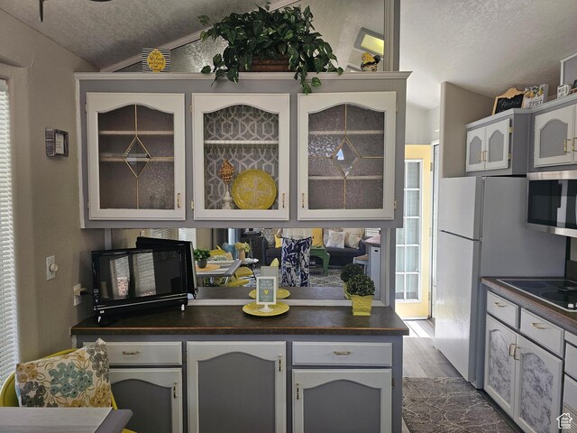 16 Mountain Vw, Hurricane, UT 84737 - kitchen with a textured ceiling, dark countertops, glass insert cabinets, and vaulted ceiling