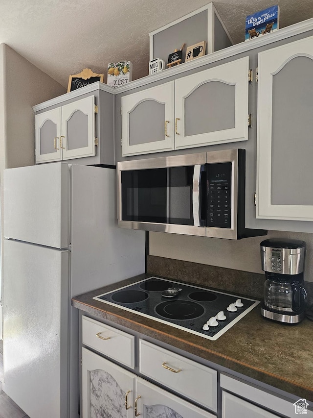 16 Mountain Vw, Hurricane, UT 84737 - kitchen featuring stainless steel microwave, white cabinets, black electric stovetop, and dark countertops