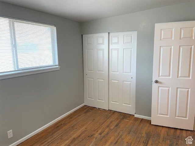 unfurnished bedroom featuring a closet, baseboards, and wood finished floors