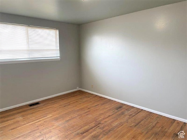 empty room featuring light wood-style floors, baseboards, and visible vents