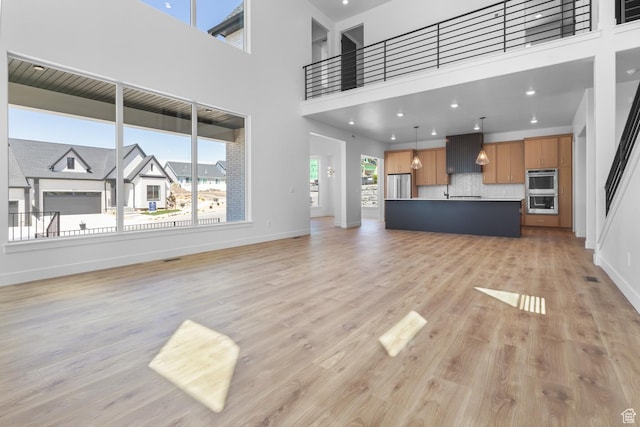 4125 N Maple Blvd W Unit 119, Lehi, UT 84043 - unfurnished living room featuring light wood-style flooring, baseboards, and a towering ceiling