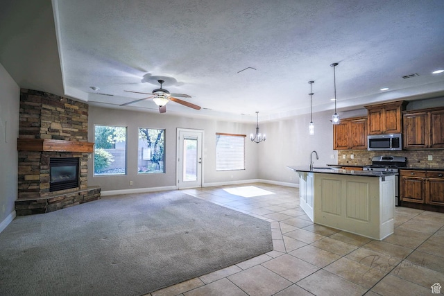kitchen with a fireplace, open floor plan, dark countertops, stainless steel appliances, and a sink