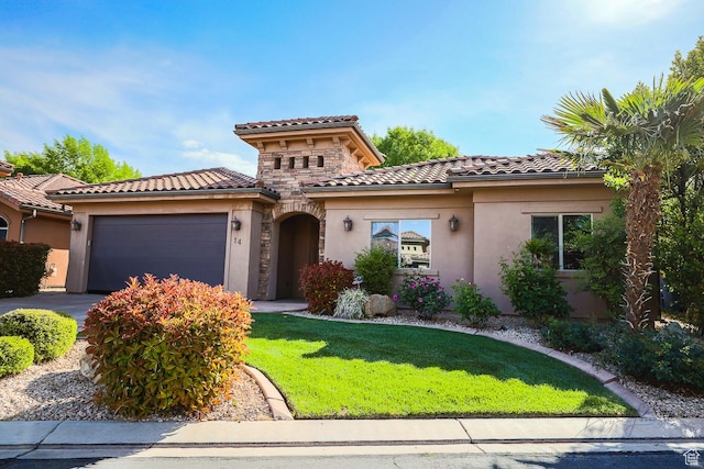 mediterranean / spanish home with a tiled roof, stucco siding, a front yard, a garage, and driveway