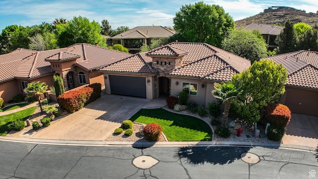 mediterranean / spanish house featuring concrete driveway, a residential view, stucco siding, an attached garage, and a tiled roof