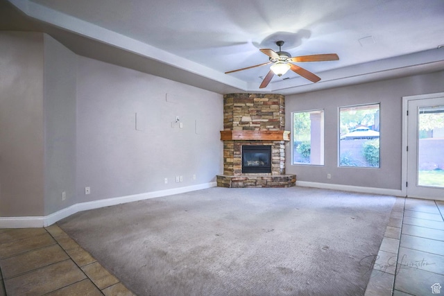 unfurnished living room with ceiling fan, a fireplace, tile patterned flooring, and baseboards