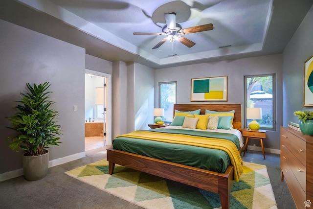carpeted bedroom featuring multiple windows, baseboards, and a raised ceiling